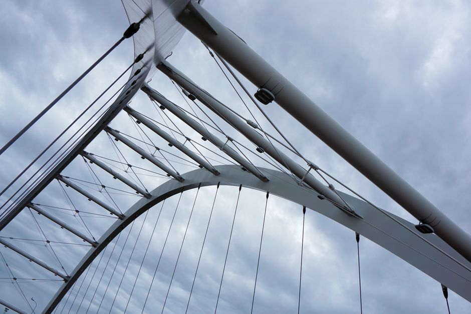 Close-up view of a modern steel bridge structure showcasing contemporary design and geometry against a cloudy sky.